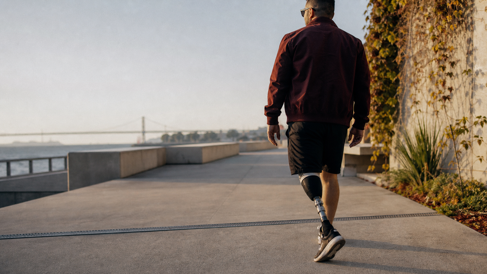 A person with a below-knee prosthesis walking along a waterfront path
