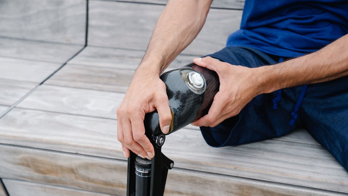 An adult adjusting their prosthetic leg outdoors, highlighting body positivity and disability representation.