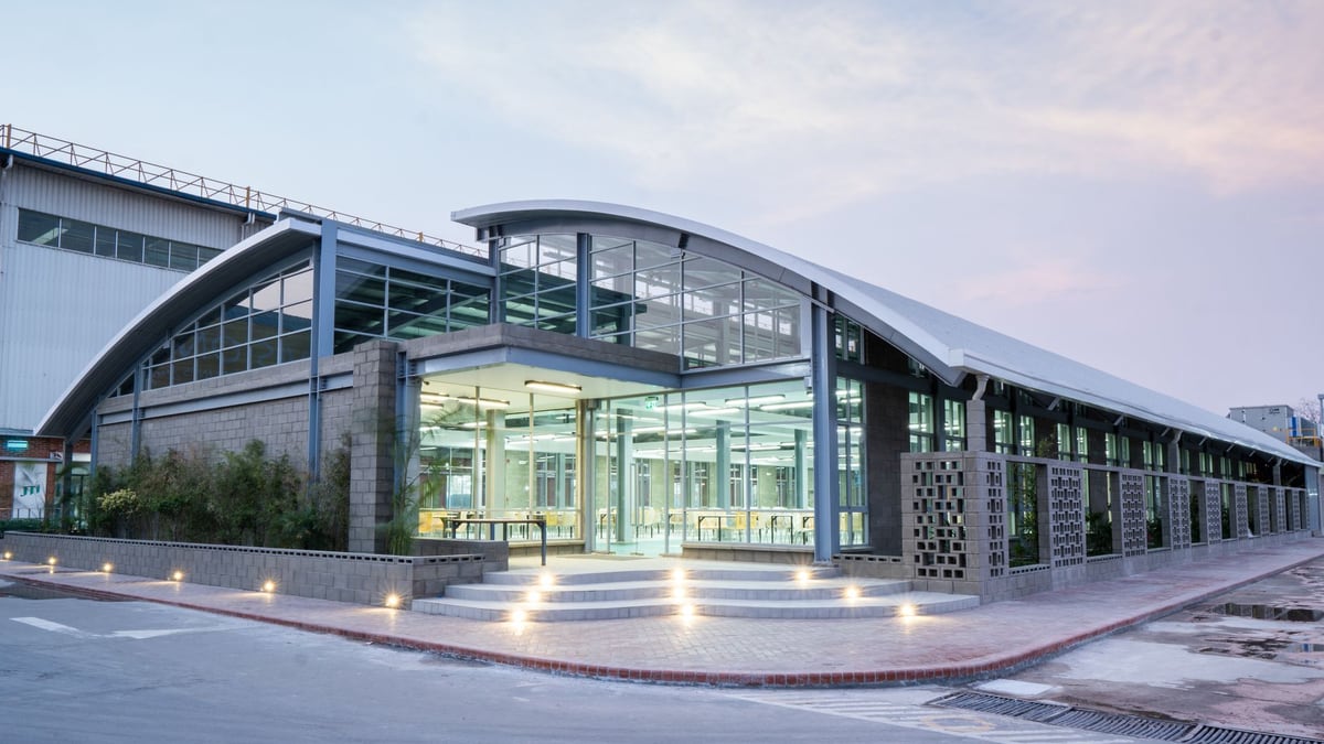 Sleek modern building with illuminated glass entrance and curved roof, showcasing urban architectural design.