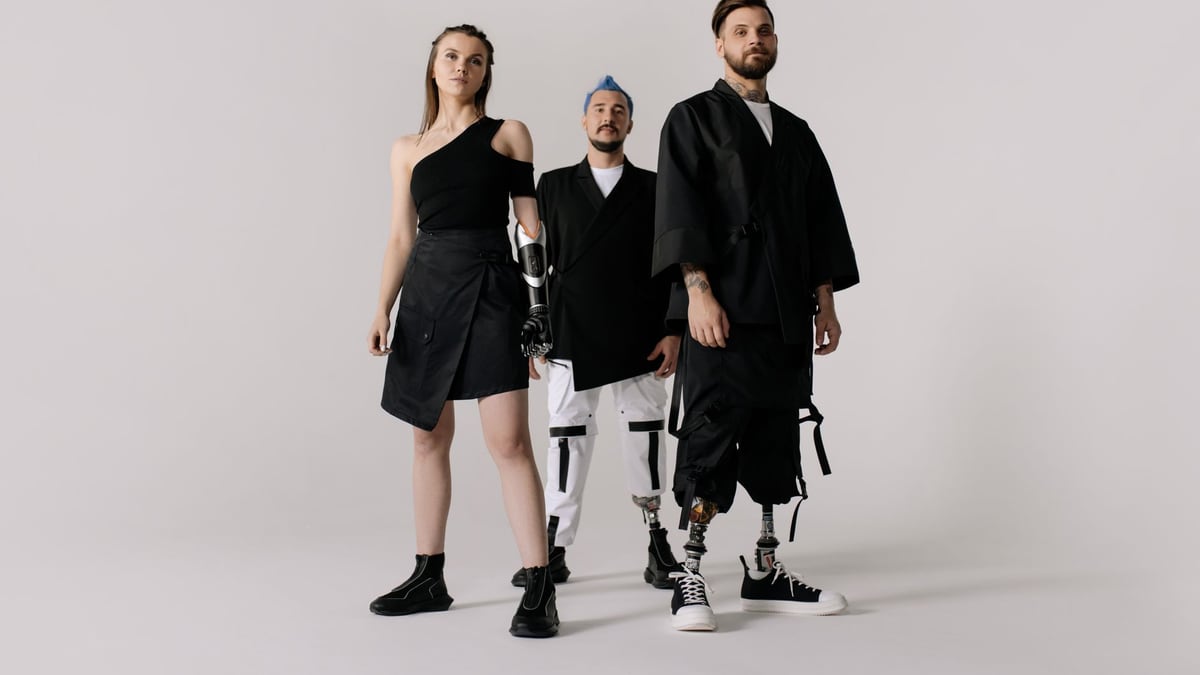 Diverse group showcasing prosthetic limbs in modern fashion on a white backdrop.